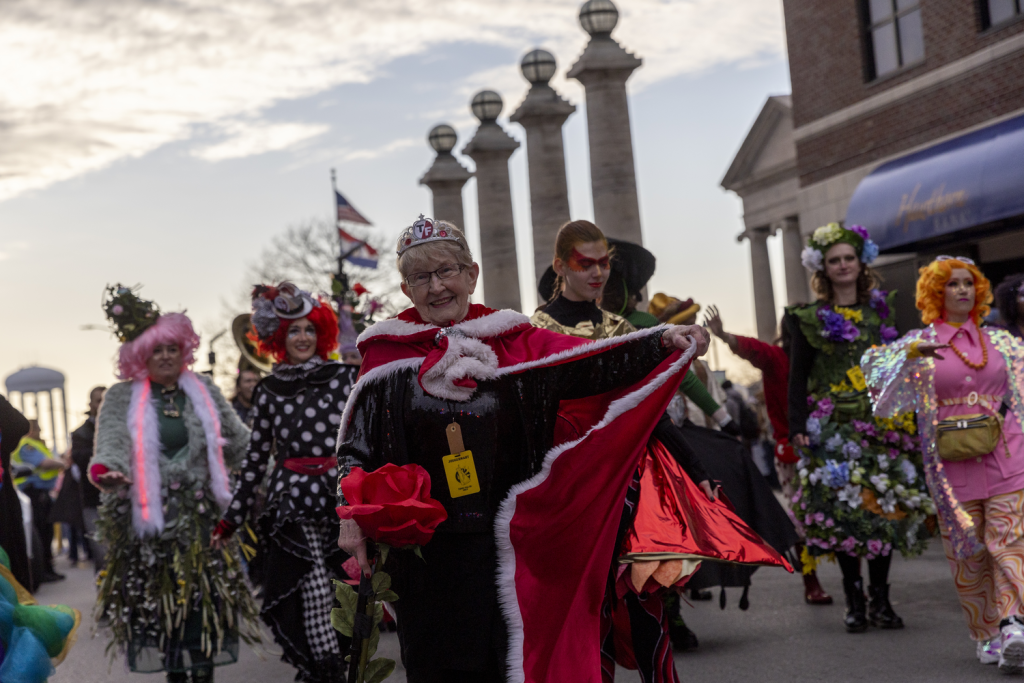 People in colorful costumes march and dance in a parade in downtown Columbia
